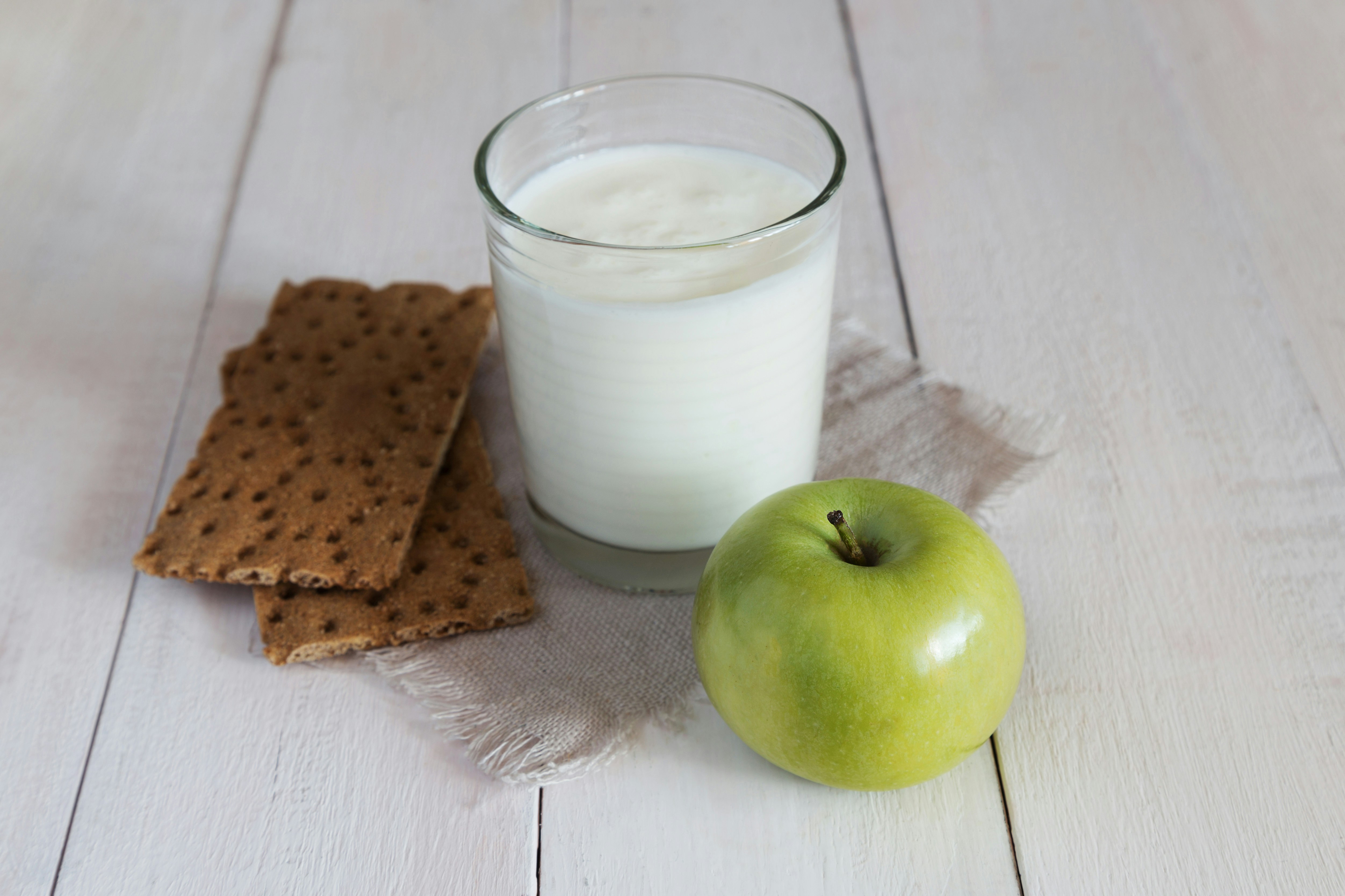 a glass of milk with a green apple and biscuits