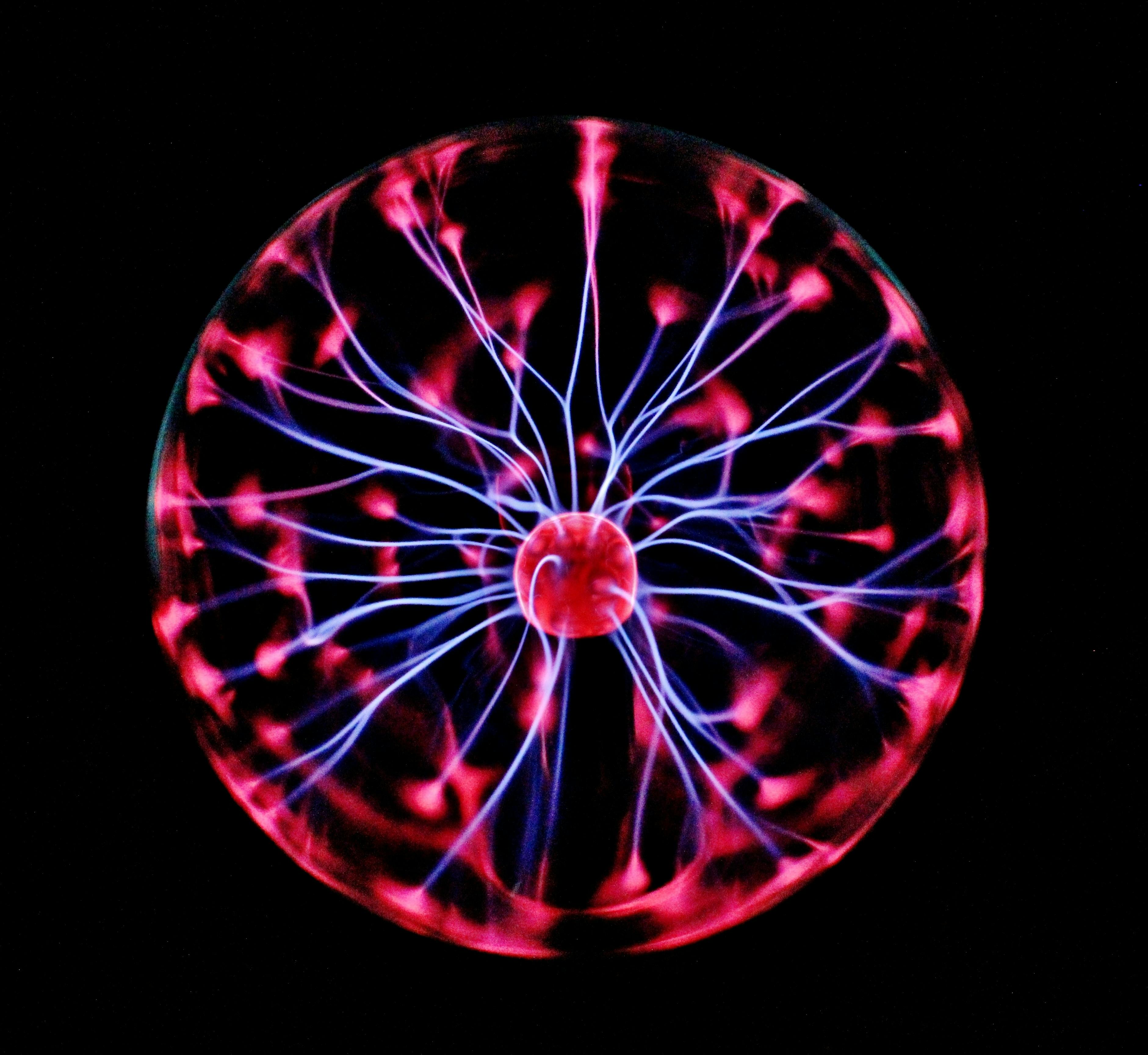 a clear sphere with whispy white/blue static elctricity glowing from a red-violet center outward to red-violet spots on the inside of the sphere