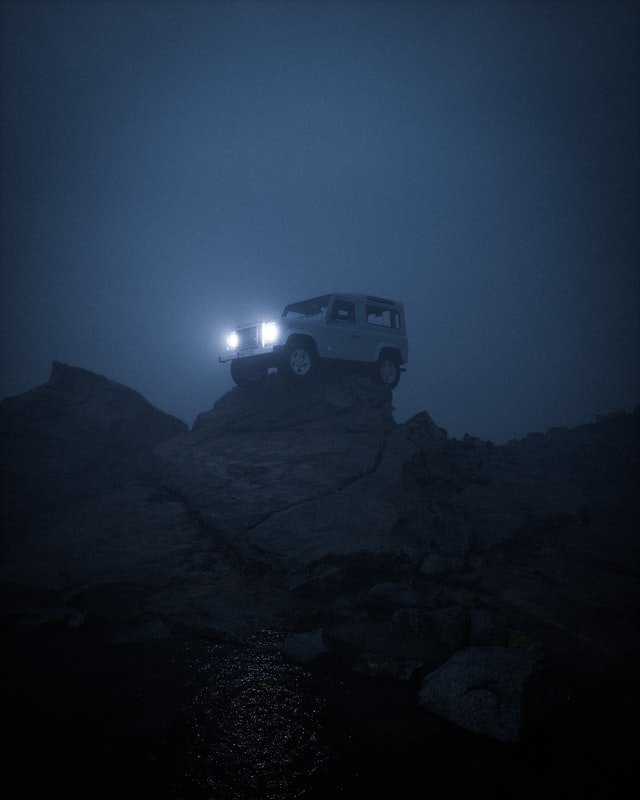 An offroad Jeep sits atop a small cliff.