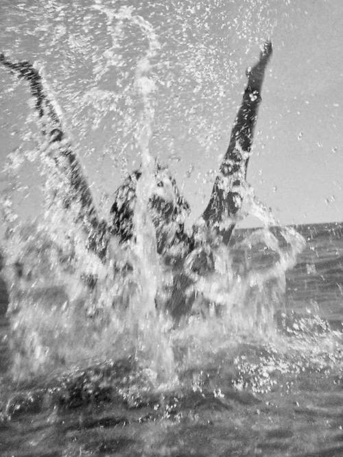 Woman splashing excidedly out of the ocean.